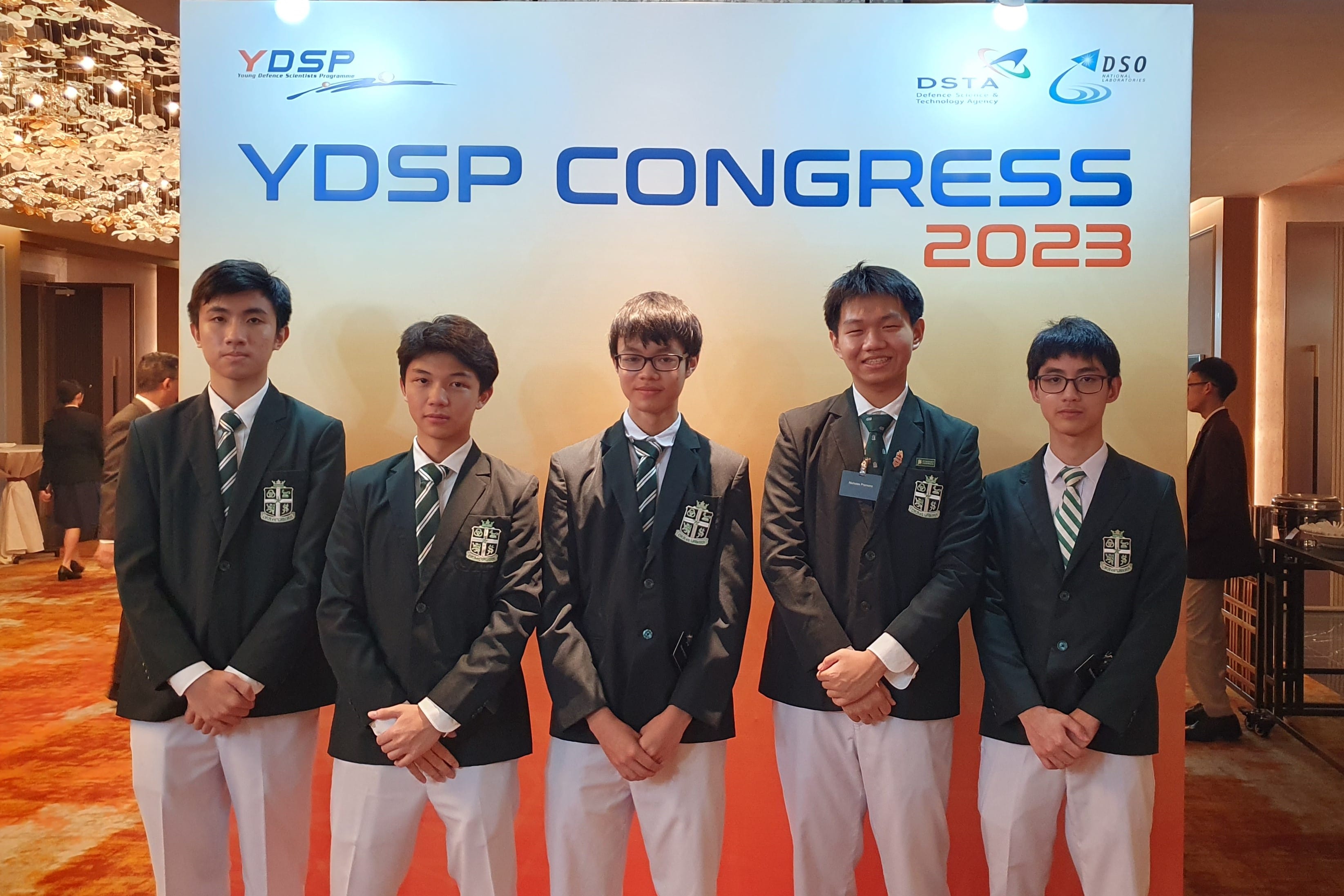 Five young male students in school blazers stand in front of a YDSP Congress 2023 banner.
